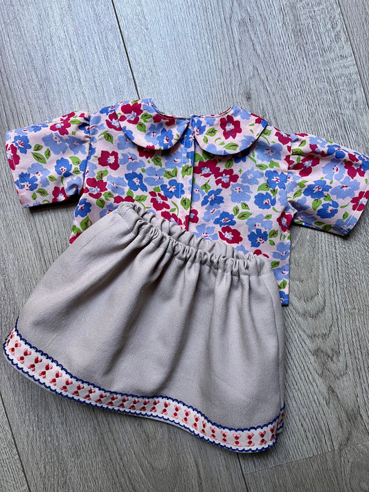 Children's dress with floral top and gray skirt on a wooden floor